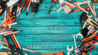 Assorted home repair tools on a rustic workbench with sunlight highlighting their textures.